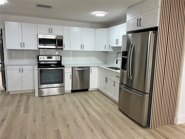 a kitchen with granite countertop a refrigerator stove and microwave