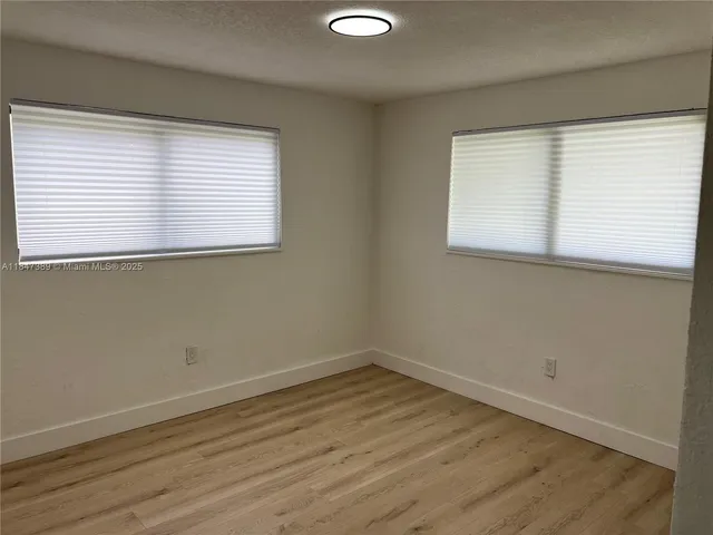 a view of a room with wooden floor and a window