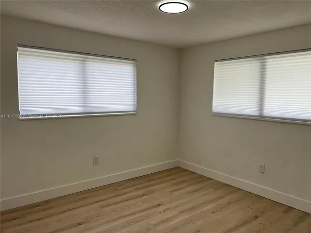 an empty room with wooden floor and a window
