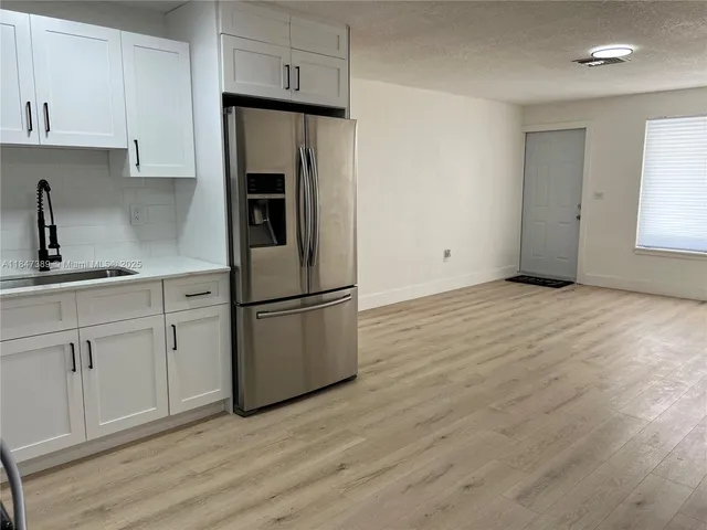 a kitchen with a refrigerator sink and cabinets