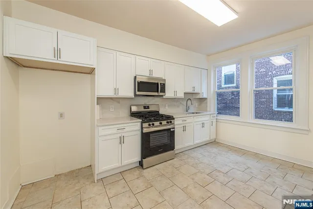 a kitchen with granite countertop a stove top oven microwave and cabinets