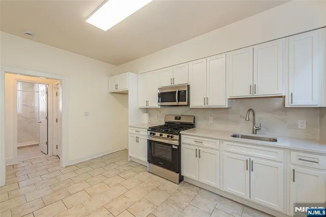 a kitchen with stainless steel appliances a stove a sink and a microwave