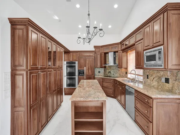 a large kitchen with kitchen island granite countertop a refrigerator oven a sink dishwasher and white cabinets with wooden floor