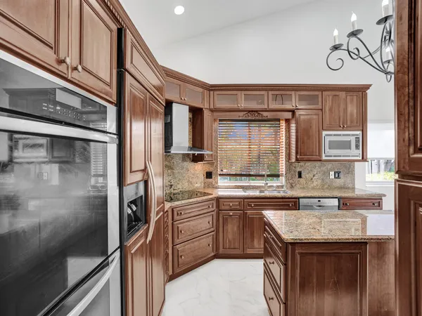 a kitchen with stainless steel appliances granite countertop a sink and a refrigerator
