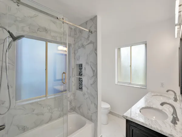 a bathroom with a granite countertop sink a toilet and shower