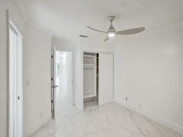 an empty room with closet and a ceiling fan