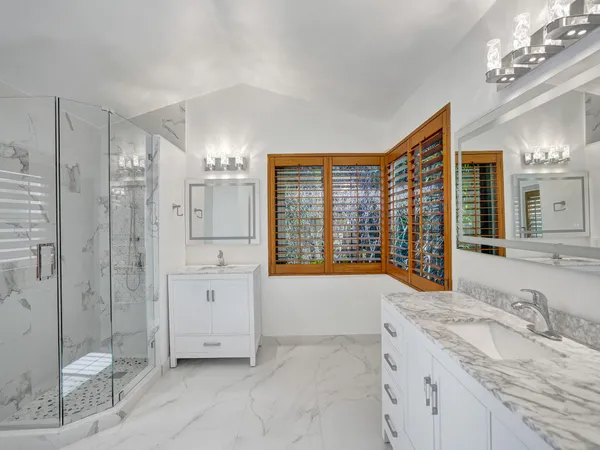 a spacious bathroom with a granite countertop sink a toilet a mirror and shower