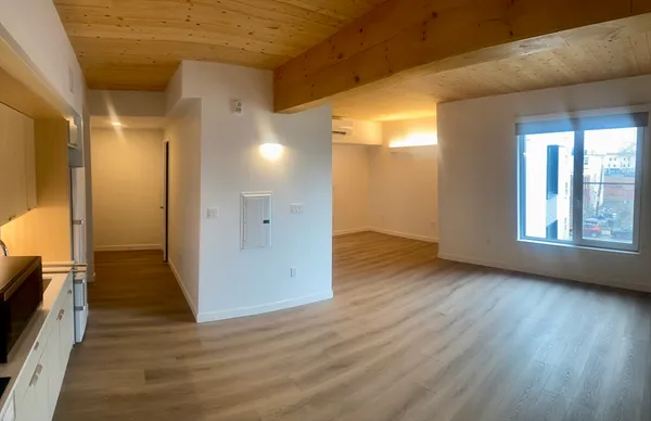 a view of a hallway with wooden floor and a bathroom