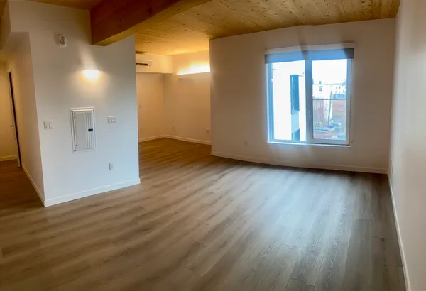a view of an empty room with wooden floor and a window