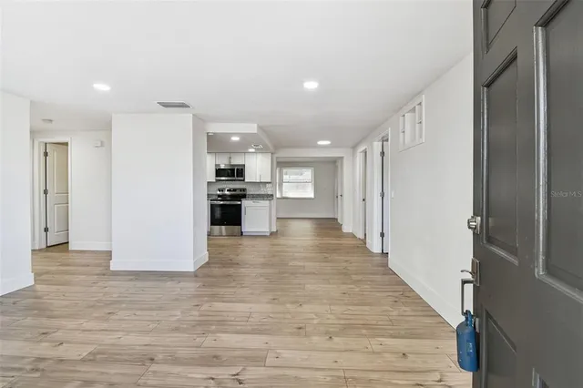a view of an empty room with wooden floor and a window