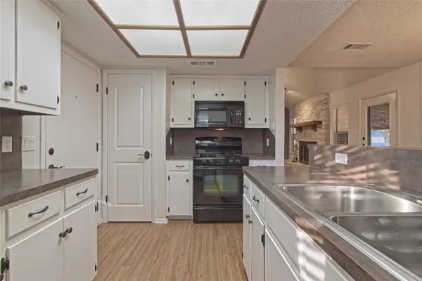 a kitchen with granite countertop white cabinets and a wooden floor