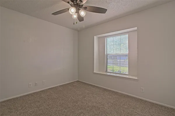 an empty room with a window and a fan