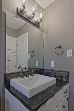 a bathroom with a granite countertop sink a toilet a mirror and bathtub