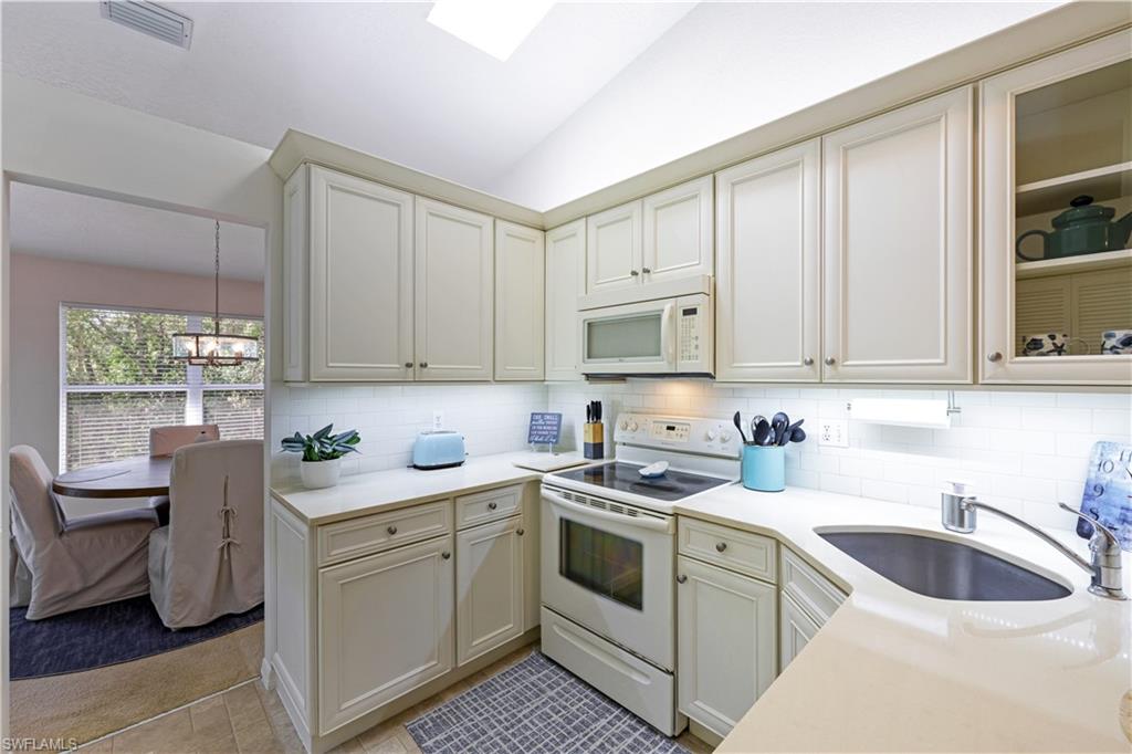 386 Emerald Bay Circle, Unit G4 Naples, FL 34110 - Photo 8 of 22 a kitchen with white cabinets sink and white appliances