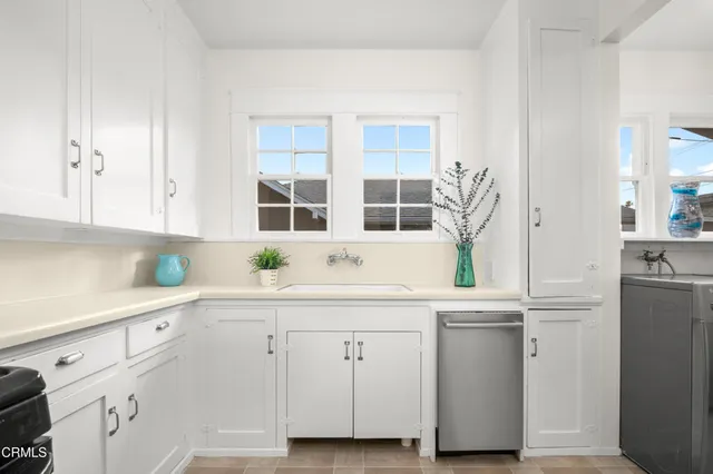 a kitchen with white cabinets and sink