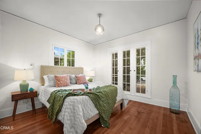 a bed sitting in a bedroom next to a window with a lamp and wooden floor
