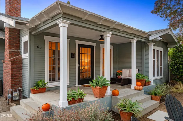front view of a house with chairs and potted plants