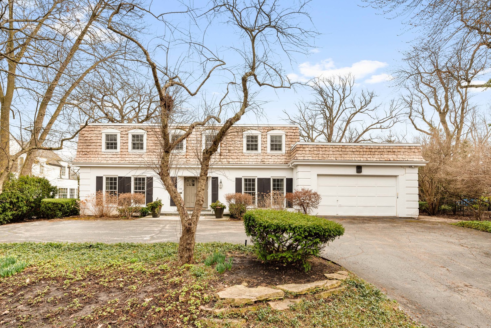 a front view of a house with garden and trees
