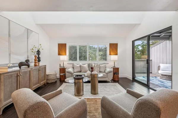 a living room with furniture kitchen view and a large window