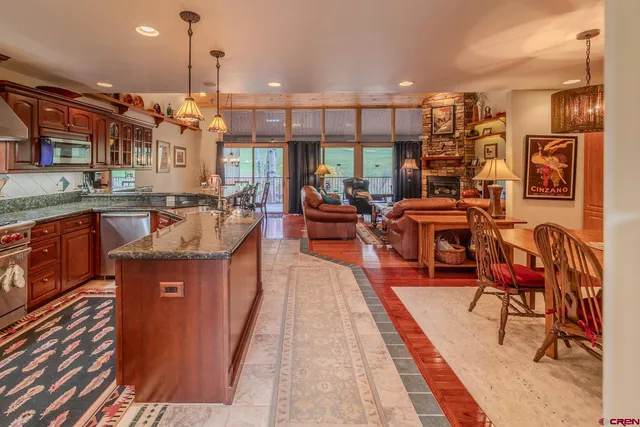 a kitchen with stainless steel appliances granite countertop a stove top oven a dining table and chairs with wooden floor