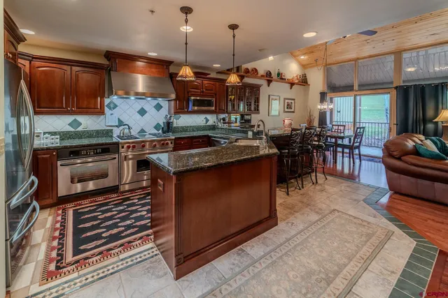 a kitchen with stainless steel appliances granite countertop a stove a sink a oven a dining table and chairs