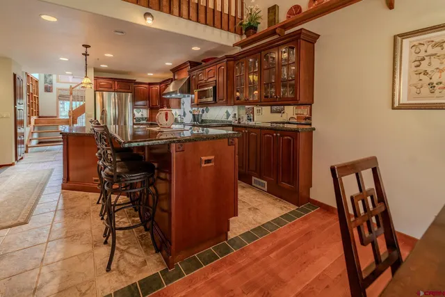 a kitchen with stainless steel appliances granite countertop a table chairs sink and cabinets