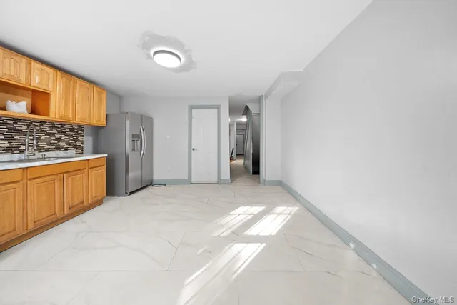 a view of a kitchen with refrigerator and white cabinets