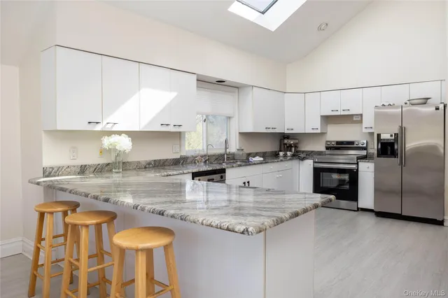 a kitchen with granite countertop a stove a sink and a refrigerator