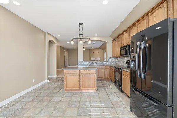 a large kitchen with stainless steel appliances kitchen island granite countertop a refrigerator and a sink