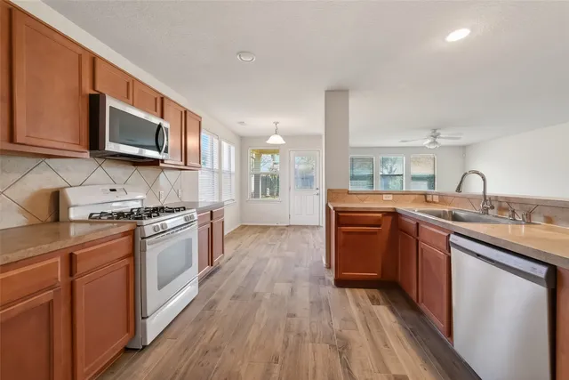 a kitchen with stainless steel appliances granite countertop a sink a stove a microwave a counter top space and cabinets