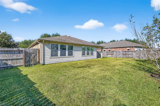 a view of a house with a yard and a large tree