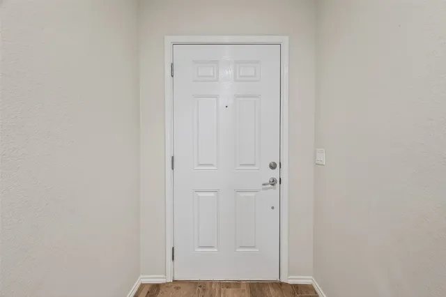 a view of a hallway with wooden floor and a bathroom