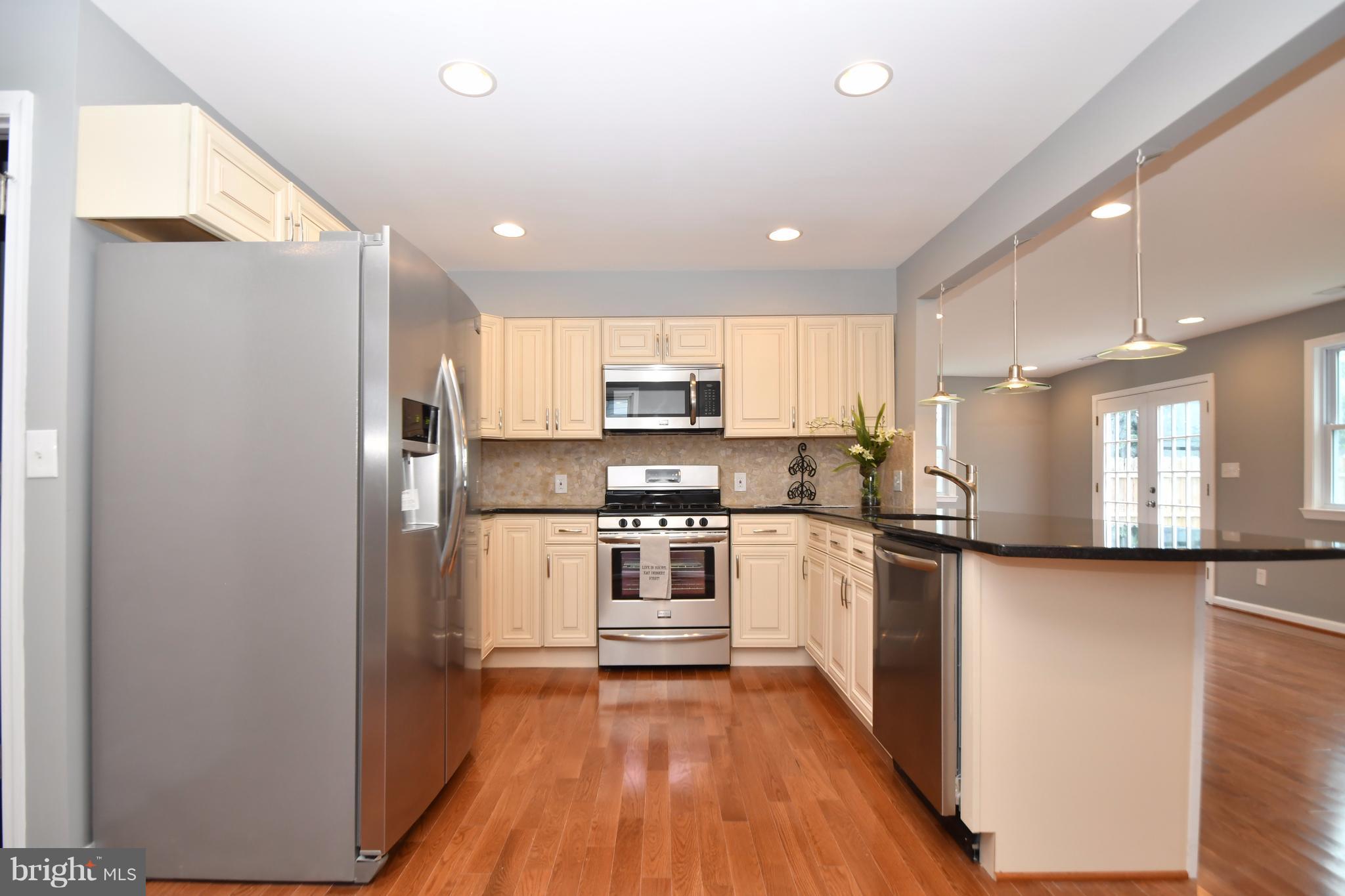 8209 Northview Road Baltimore, MD 21222 - Photo 4 of 30 a kitchen with stainless steel appliances granite countertop a refrigerator a sink dishwasher a stove and white countertops with wooden floor