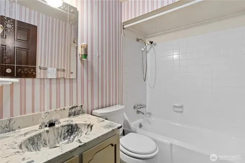 a bathroom with a granite countertop sink a toilet and shower