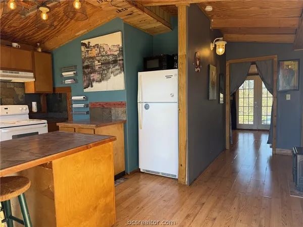 a kitchen with stainless steel appliances granite countertop a refrigerator a stove and a sink with wooden floor