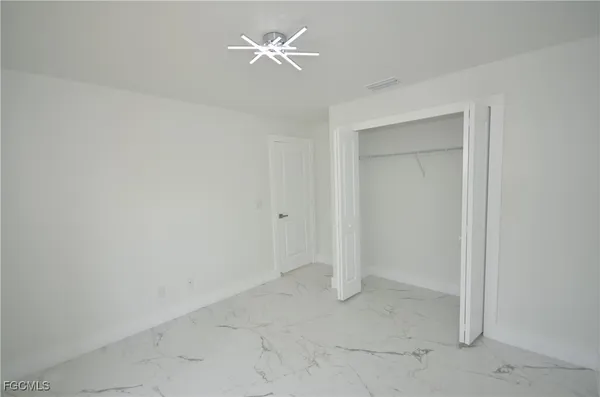 an empty room with closet and a ceiling fan