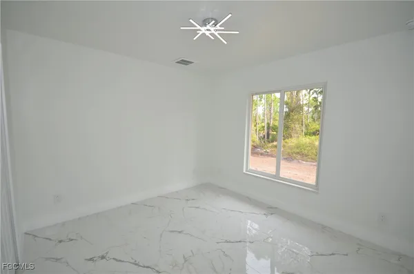 an empty room with a window and a fan