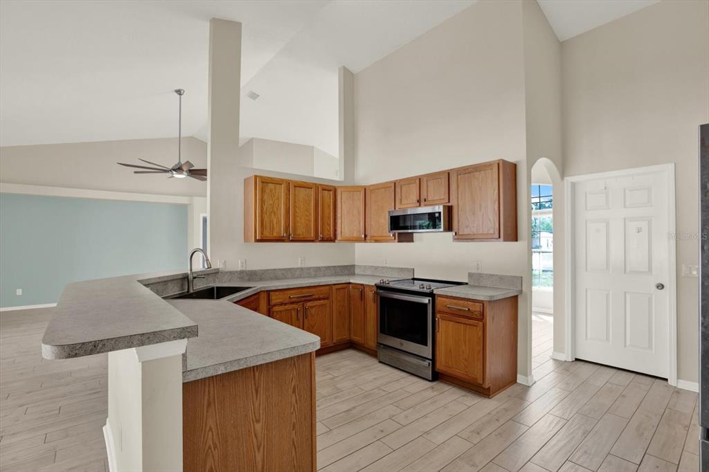4400 Dior Road Spring Hill, FL 34609 - Photo 16 of 37 a kitchen with stainless steel appliances granite countertop a sink stove and refrigerator