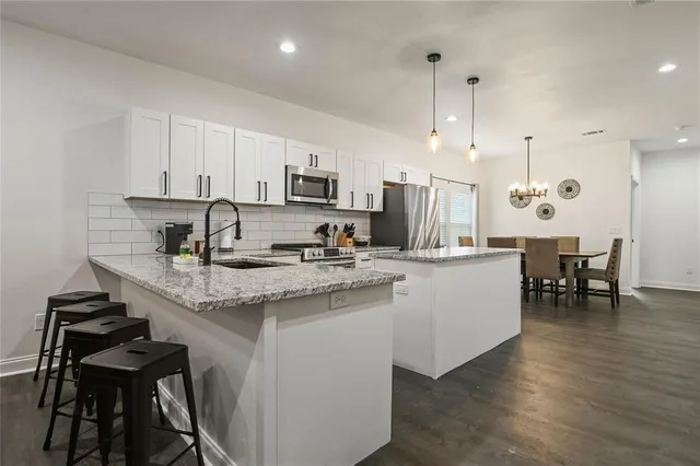 a kitchen with kitchen island granite countertop a sink a center island stainless steel appliances and cabinets