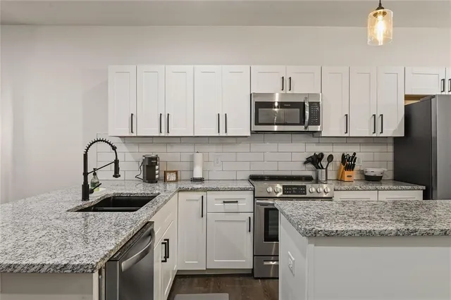 a kitchen with granite countertop a sink a stove and cabinets