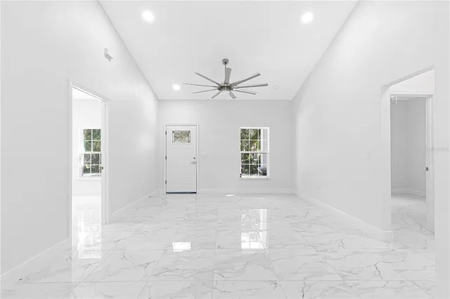 an empty room with windows and ceiling fan