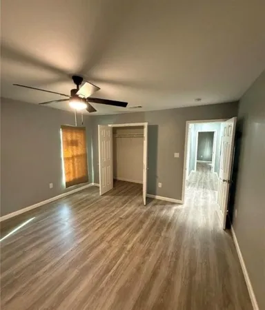 a view of an empty room with wooden floor and a window