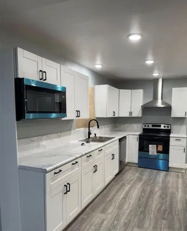 a kitchen with granite countertop white cabinets and stainless steel appliances