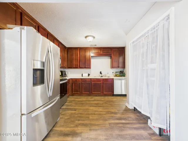 a kitchen with stainless steel appliances granite countertop a refrigerator stove a sink dishwasher and microwave with wooden cabinets