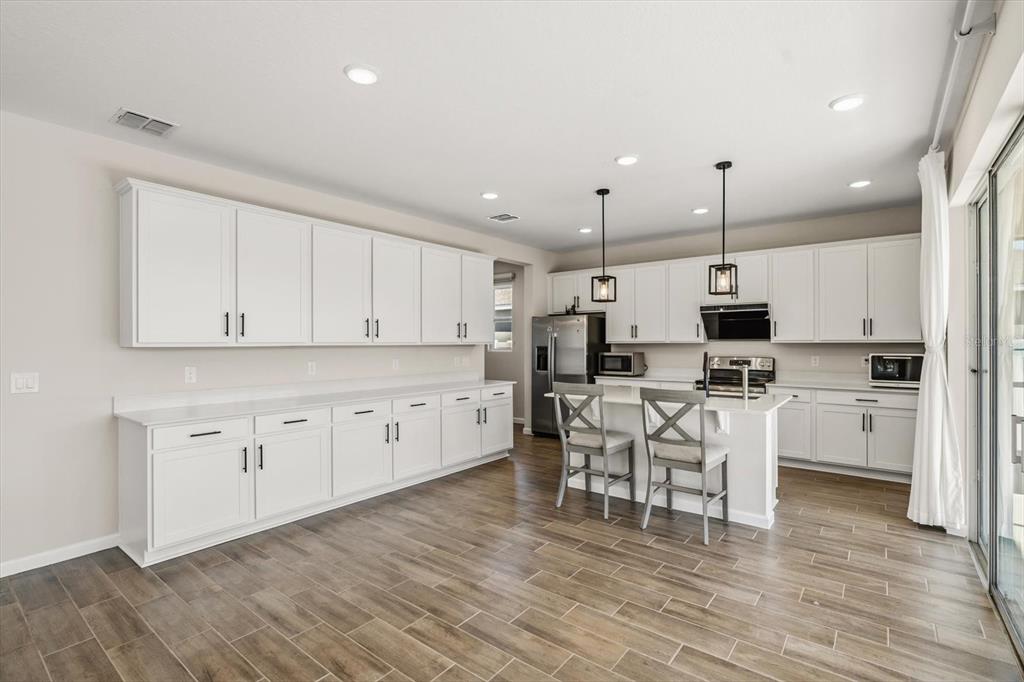 3657 Sublett Loop Tavares, FL 32778 - Photo 3 of 39 a large white kitchen with lots of counter space wooden floor and appliances