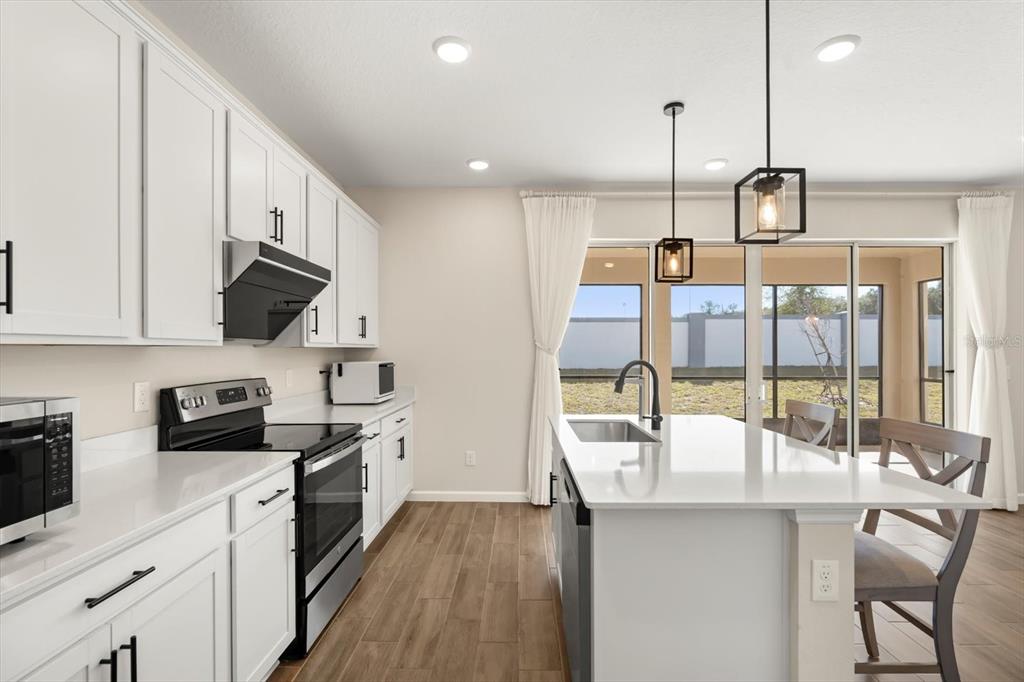3657 Sublett Loop Tavares, FL 32778 - Photo 8 of 39 a kitchen with stainless steel appliances granite countertop a sink a stove and a wooden floors