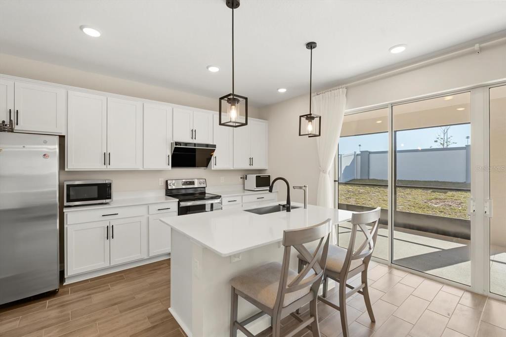 3657 Sublett Loop Tavares, FL 32778 - Photo 9 of 39 a kitchen with stainless steel appliances kitchen island granite countertop a stove a sink a refrigerator with a dining table and chairs