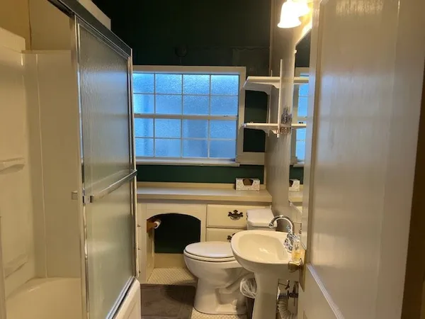 an empty room with wooden floor closet and windows