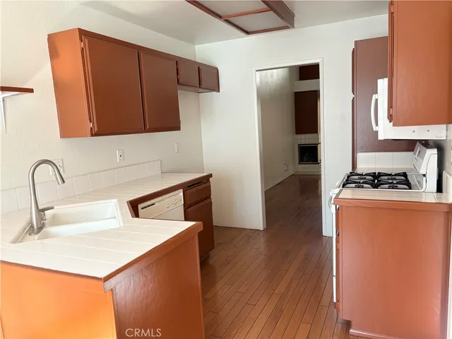a kitchen with stainless steel appliances granite countertop a sink stove and refrigerator with wooden floor