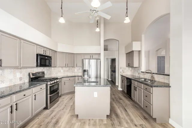 a large kitchen with stainless steel appliances lots of counter space sink refrigerator and cabinets